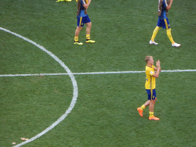 Eine Gruppe von Männern in Fußballtrikots feiert auf einem Feld, indem sie klatschen.