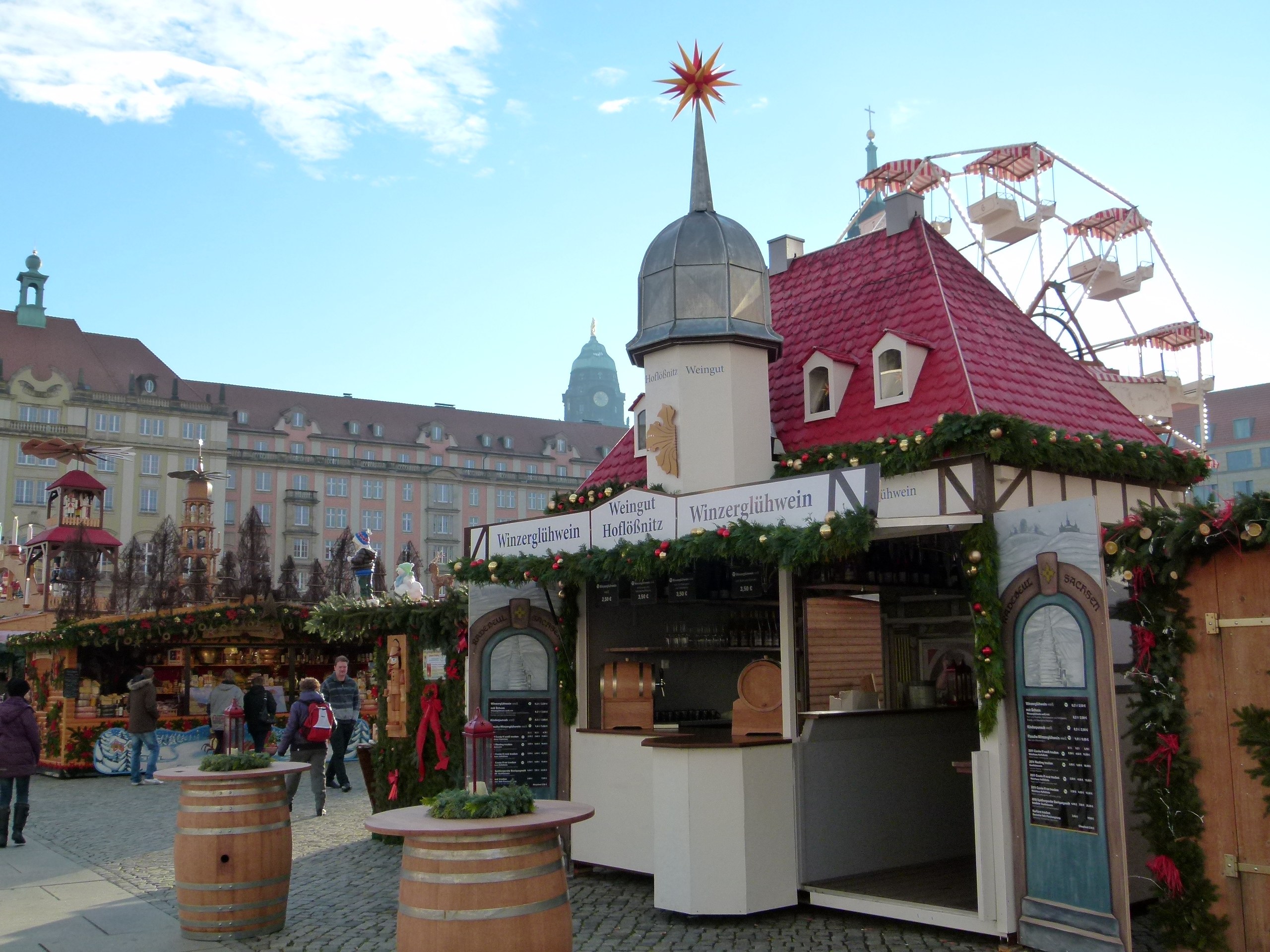Ein geschäftiger Weihnachtsmarkt in Nürnberg, Deutschland mit Menschen um geschmückte Stände, festliche Lichter, ein Riesenrad, Gebäude und ein Schild.