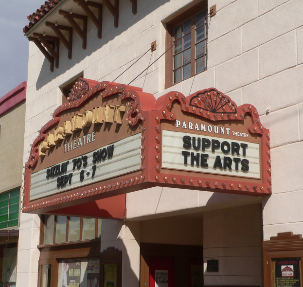 Außenansicht des Paramount Theatre in Sacramento, Kalifornien, mit Glasfenstern und -türen und einem "Support the Arts"-Schild, unter einem sichtbaren Himmel.