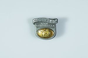 Eine Silber- und Goldnadel mit einem Männerbildnis, die das 80-jährige Jubiläum der Olympischen Spiele in Moskau feiert, mit einer Inschrift darauf.