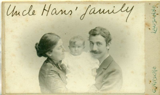 Ein altes Foto eines Mannes im Anzug und Krawatte, einer Frau mit einem Baby auf dem Arm, mit der Aufschrift "Onkel Hans' Familie" oben drauf, alle strahlend.