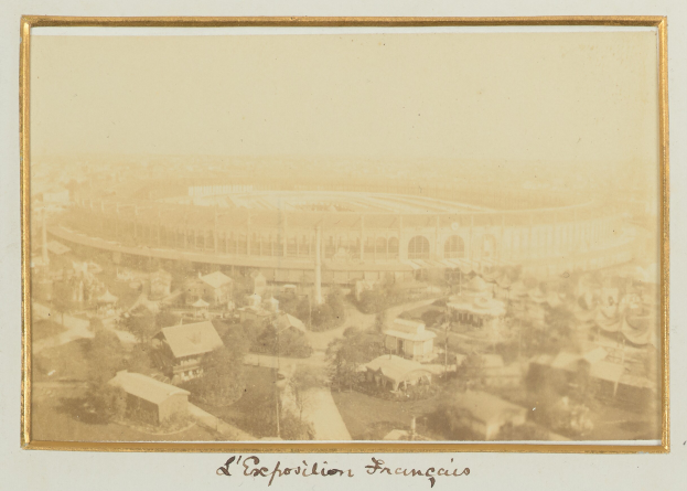 Altes Schwarz-Weiß-Foto eines Stadions in städtischer Umgebung, umgeben von Gebäuden, Bäumen und Strommasten, mit Text am unteren Rand.