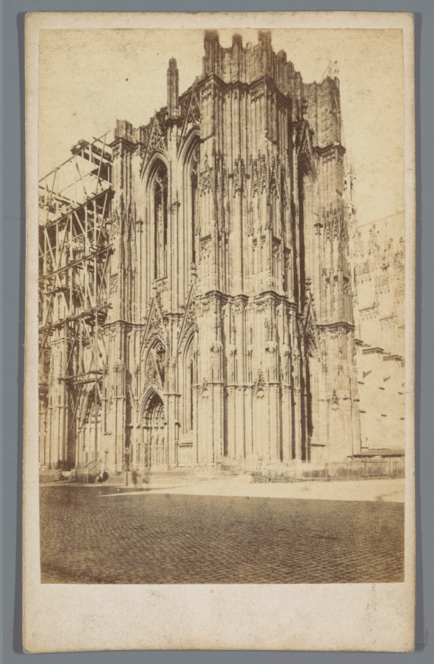 Ein Schwarz-Weiß-Foto einer großen, fensterreichen Kathedrale mit detaillierten Verzierungen, vor einem grauen Hintergrund.