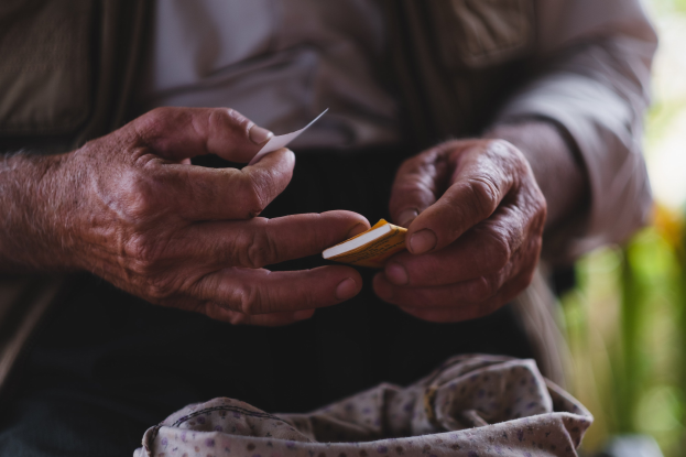 Alter Mann hält ein Blatt Papier und sieht besorgt aus, mit unscharfem Hintergrund, wahrscheinlich wegen Demenz.