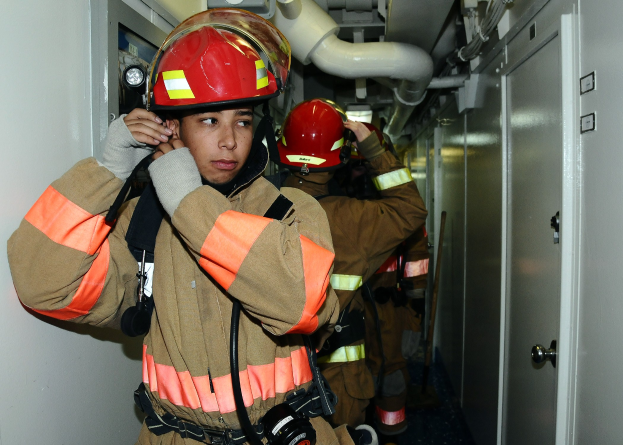 Feuerwehrleute in Uniform in einem Raum mit Rohren und Ausrüstung während einer Übung