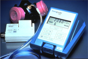 Eine Gasmasken liegt auf einem Tisch neben einem elektronischen Gasdetektionsgerät mit einem angeschlossenen Kabel.