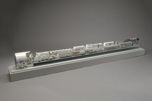 Ein detailliertes Modell des neuen Wasserstoff-Brennstoffzellensystems von Sainsbury's, das einen Kraftstofftank, einen Filter, eine Einspritzdüse und eine Energiequelle umfasst, die alle auf einer weißen Oberfläche miteinander verbunden sind.