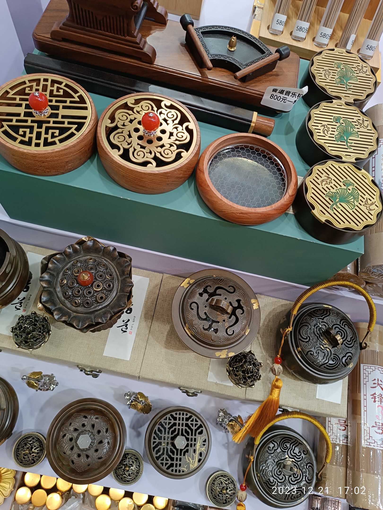 Eine Sammlung chinesischer Räucherstäbchenbrenner, Schachteln und Papiere mit Text darauf, die auf einem Tisch arrangiert sind, wahrscheinlich für ein chinesisches Neujahrsfest.