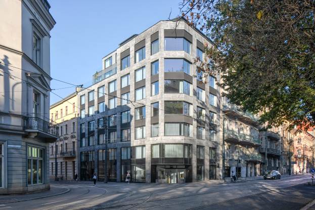 Großes Bürogebäude mit zahlreichen Fenstern, umgeben von Straßeninfrastruktur, Fahrzeugen, Fußgängern, Bäumen und einem bewölkten Himmel, das als Firmensitz dient.