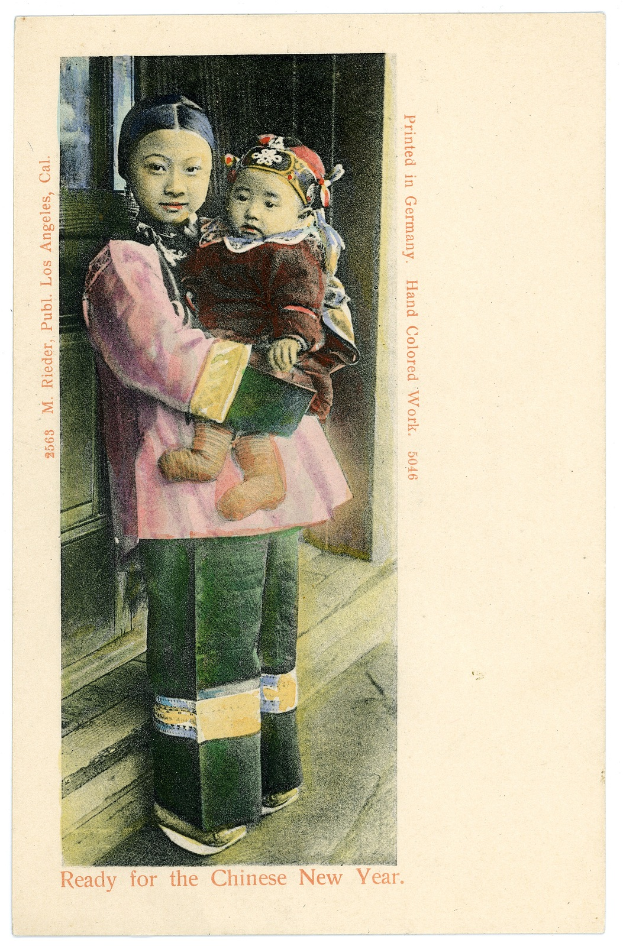 Eine alte Postkarte mit einer Frau, die ein Baby im Arm hält und beide fröhlich in die Kamera schauen, mit einer Inschrift, die wahrscheinlich 'Frohes neues Jahr' wünscht.