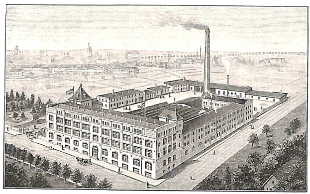Alte Fabrik mit einem großen Hauptgebäude, umgeben von Bäumen und Text unten.