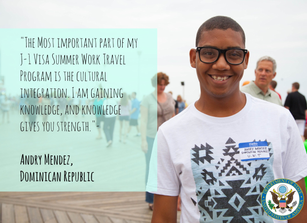 Ein Mensch in einem weißen T-Shirt lächelt, während er mit einer Gruppe auf einer hölzernen Oberfläche geht, mit einem Zitat über kulturelle Integration von Andry Mendez auf der linken Seite, Gebäuden und einem klaren blauen Himmel im Hintergrund.