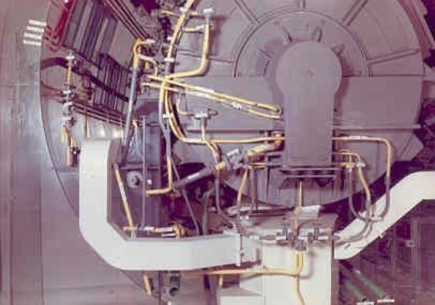 Großes industrielles Beschleunigergerät mit mehreren angeschlossenen Komponenten und Kabeln in einem Gebäude.