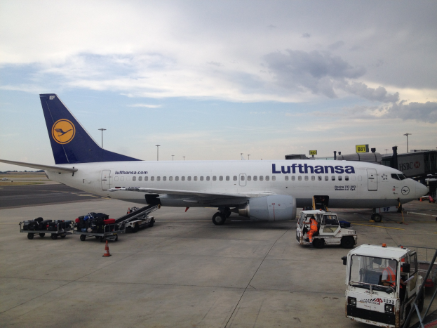 Lufthansa Airbus A320-200 am Frankfurter Flughafen mit Bodenfahrzeugen, Verkehrskegeln und Beschilderung bei bewölktem Himmel.